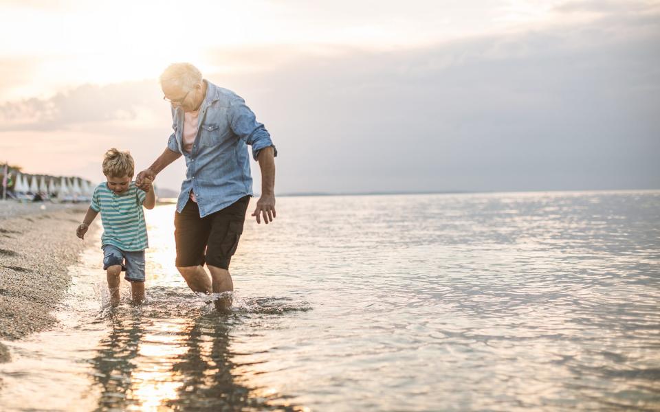 grandparent and grandchild at the beach - Getty 