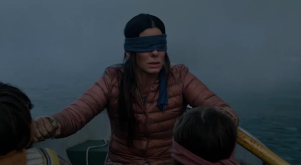 Malorie blindfolded and rowing a boat with Boy and Girl in "Bird Box"