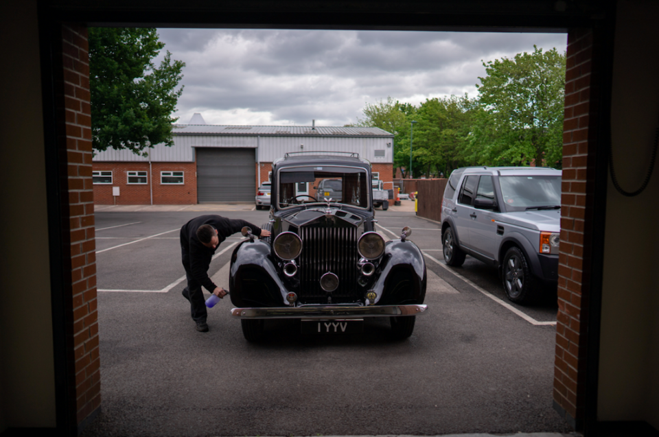 A worker cleans a funeral car to maintain respect for those that have passed away.