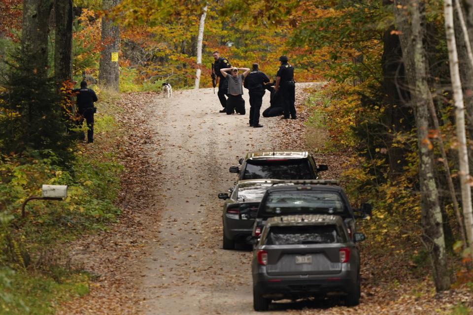 Law enforcement detain a man and woman during a manhunt for the suspect of this week's deadly mass shootings, Friday, Oct. 27, 2023, in Durham, Maine. Police are still searching for the suspect who killed at least 18 people in separate shootings at a bowling alley and restaurant in Lewiston, Maine, on Wednesday. (AP Photo/Robert F. Bukaty)