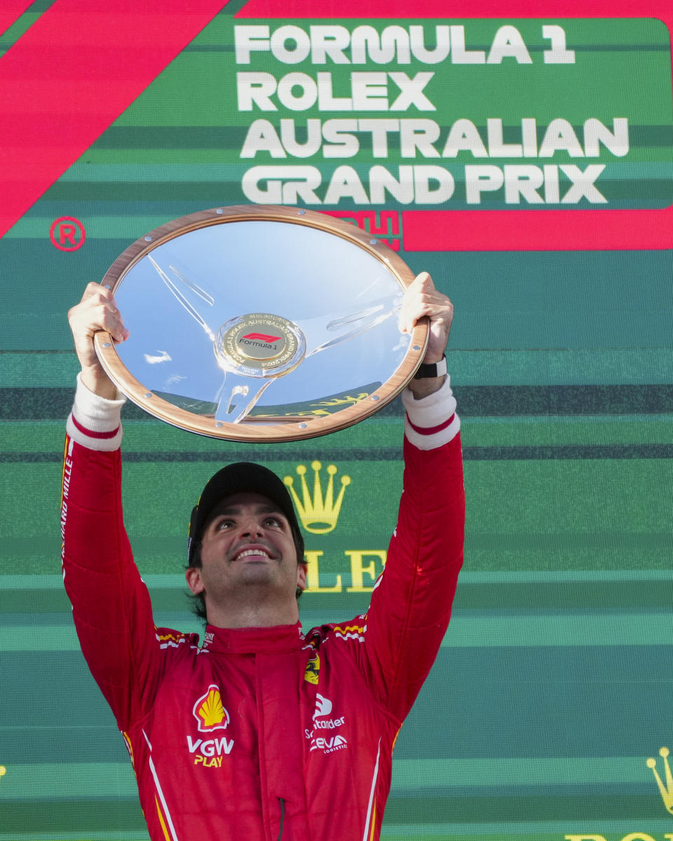 Ferrari driver Carlos Sainz of Spain holds his trophy aloft on the podium after winning the Australian Formula One Grand Prix at Albert Park, in Melbourne, Australia, Sunday, March 24, 2024. (AP Photo/Scott Barbour)