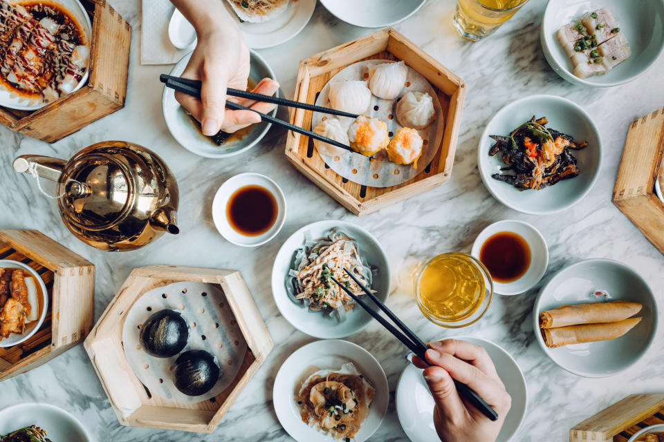 Person dining at a table with various dim sum dishes and tea, indicating a business meal or networking event