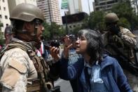 A demonstrator reacts in front of a soldier during a protest against the increase in the subway ticket prices in Santiago