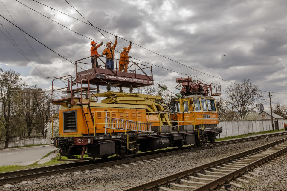 Un grupo de trabajadores reparan la infraestructura el&#xe9;ctrica da&#xf1;ada a lo largo de una v&#xed;a f&#xe9;rrea en Bucha, Ucrania, el domingo 1 de mayo de 2022. (Daniel Berehulak/The New York Times)
