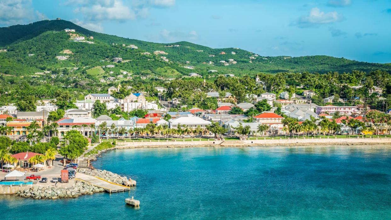 Beautiful scenery with harbor of St Croix, green mountain, water and town along the coastline.