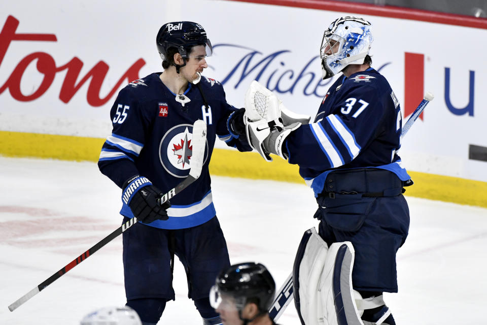 Winnipeg Jets goaltender Connor Hellebuyck (37) and Mark Scheifele (55) celebrate the team's win over the Tampa Bay Lightning in an NHL hockey game Tuesday, Jan. 2, 2024, in Winnipeg, Manitoba. (Fred Greenslade/The Canadian Press via AP)