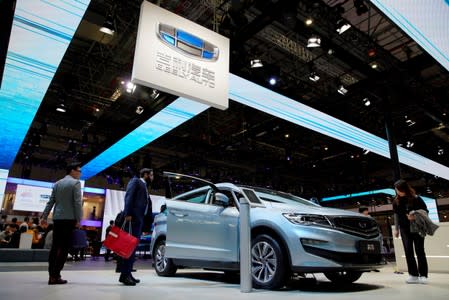 FILE PHOTO: Visitors look at a Geely Jiaji vehicle displayed during the media day for the Shanghai auto show in Shanghai