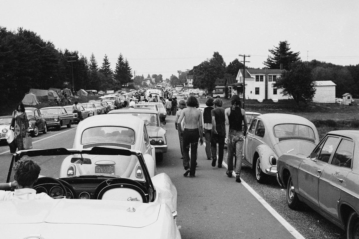 Members of the American youth subculture generally termed 'hippies' walk along roads choked with traffic on the way to the large rock conert called Woodstock, Bethel, New York, August, 1969