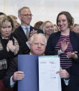 Surrounded by DFL legislators, Minnesota Gov. Tim Walz holds up a bill he signed that adds a "fundamental right" to abortion access into state law in St. Paul, Minn., on Tuesday, Jan. 31, 2023. Behind him, from left to right, are first lady Gwen Walz, Tim Stanley of Planned Parenthood and Rep. Carlie Kotyza-Witthuhn, DFL-Eden Prairie. Walz's signature makes Minnesota the sixteenth state to spell out a right to abortion access in its law books or constitution, and the first state Legislature to take such action since Roe v. Wade was overturned in June 2022. (Glen Stubbe/Star Tribune via AP)