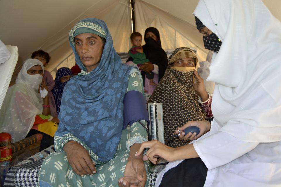 A nurse checks the blood pressure of Shakeela Bibi who is pregnant, in a clinic setup in a tent at a relief camp for flood victims, in Fazilpur near Multan, Pakistan, Sept. 24, 2022. Pregnant women are struggling to get care after Pakistan’s unprecedented flooding, which inundated a third of the country at its height and drove millions from their homes. The UN says around 130,000 pregnant women in flood-hit areas require urgent healthcare and more than 2,000 are giving birth every day, most in unsafe conditions. (AP Photo/Shazia Bhatti)