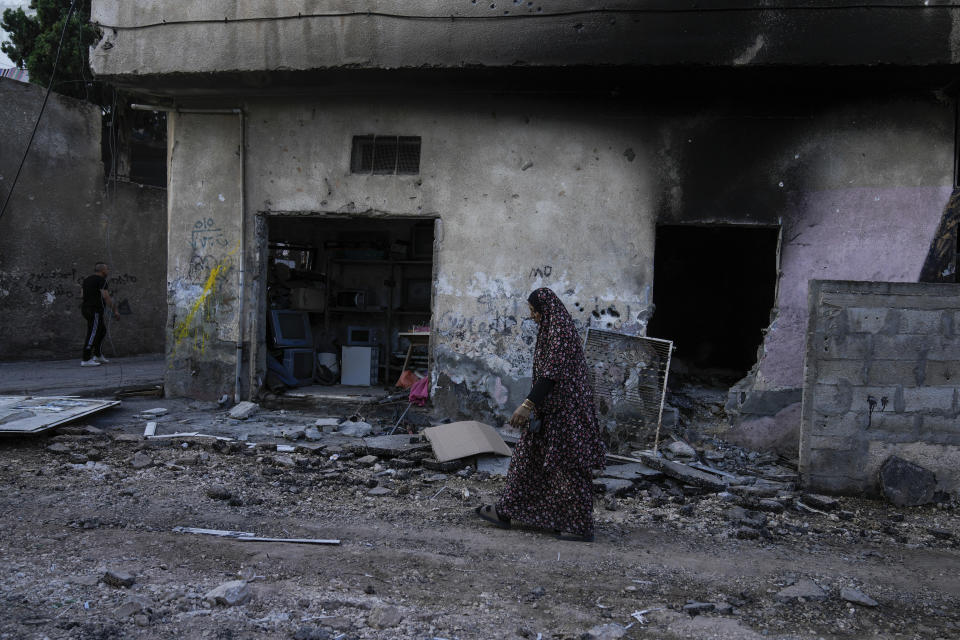 Palestinians walk on a damaged road in the Jenin refugee camp in the West Bank, Wednesday, July 5, 2023, after the Israeli army withdrew its forces from the militant stronghold. The withdrawal of troops from the camp ended an intense two-day operation that killed at least 13 Palestinians, drove thousands of people from their homes and left a wide swath of damage in its wake. One Israeli soldier was also killed. (AP Photo/Majdi Mohammed)