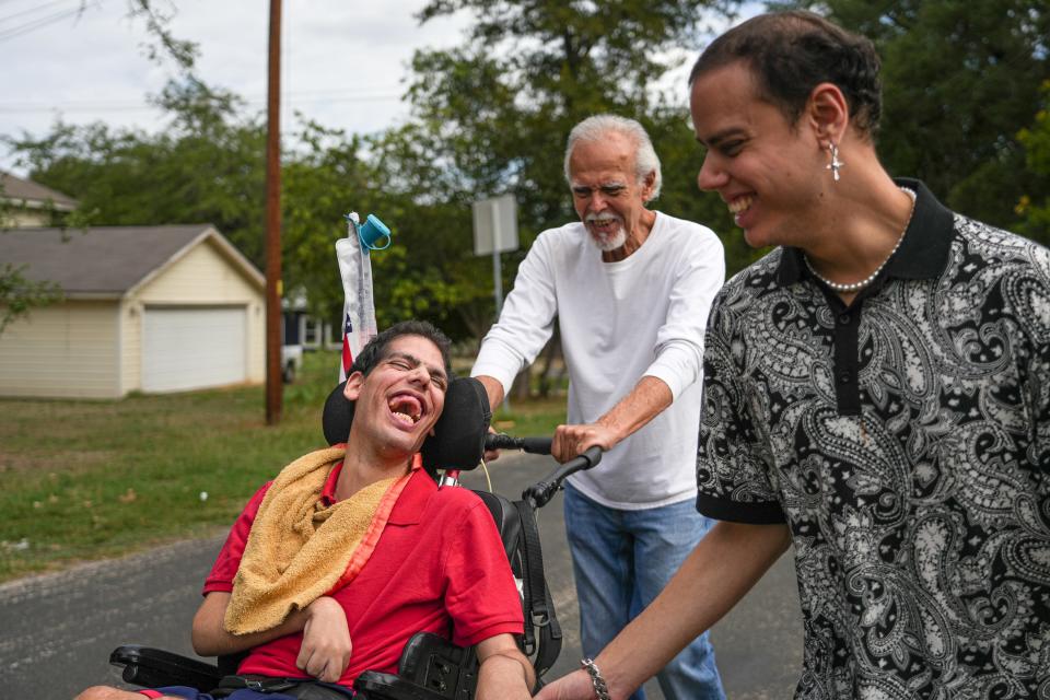 Casey Campos, right, holds his brother Cody Campos's hand while out for a walk near their West Austin home on Oct. 13, 2023.