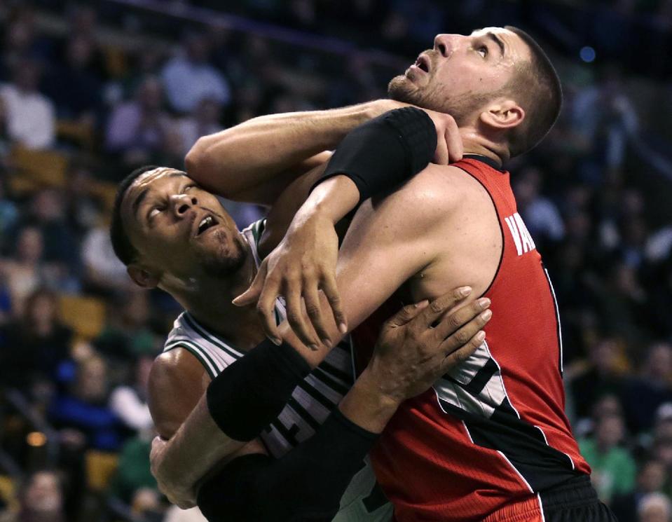 Boston Celtics forward Jared Sullinger, left, tangles with Toronto Raptors center Jonas Valanciunas on a rebound during the first quarter of an NBA basketball game in Boston, Wednesday, Jan. 15, 2014. (AP Photo/Charles Krupa)