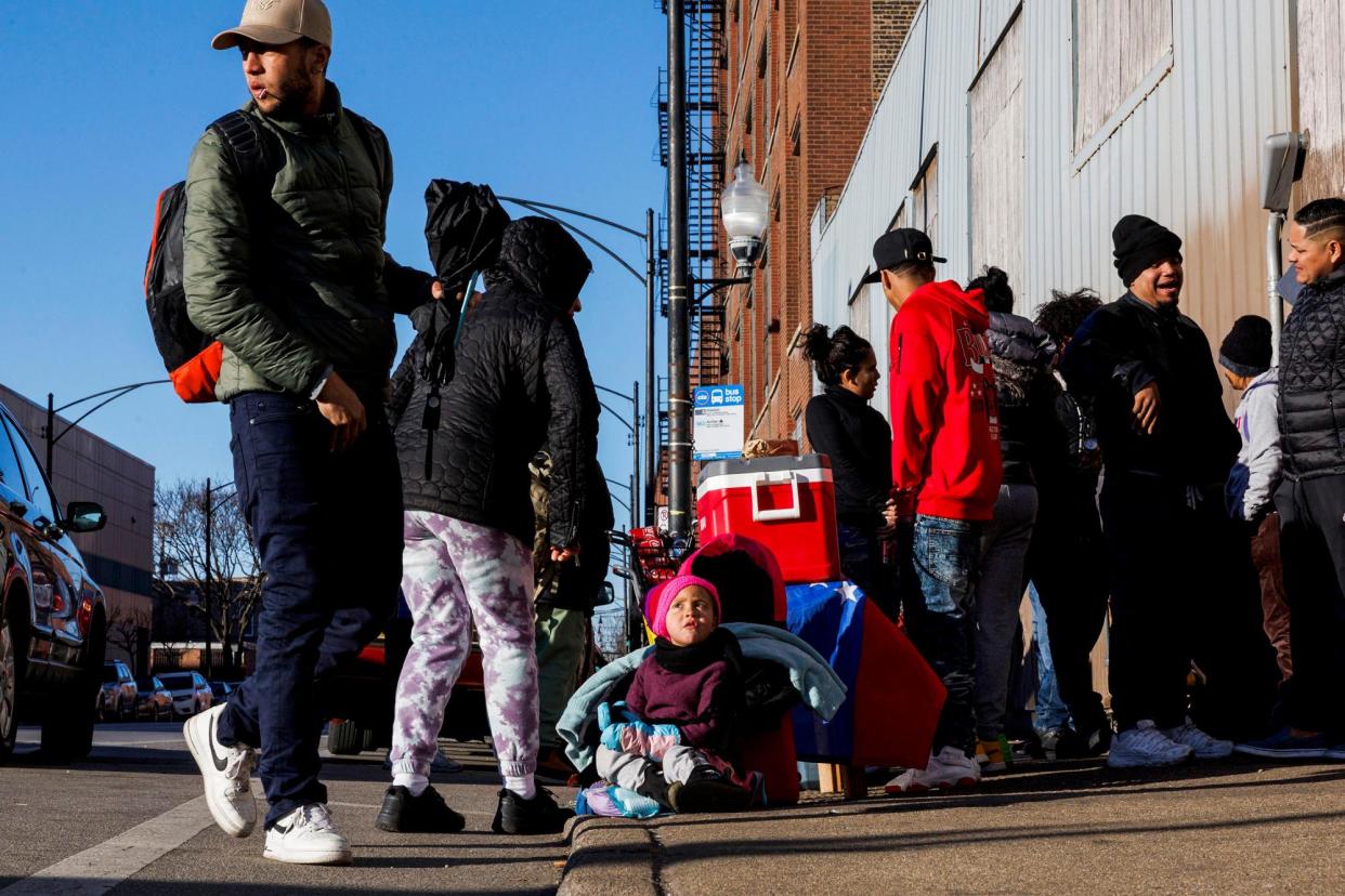 <span>A three-year-old Venezuelan girl sits next to her mother as she is selling food outside a migrant shelter in Chicago on 15 February 2024.</span><span>Photograph: Armando L. Sanchez/Chicago Tribune via Getty Images</span>