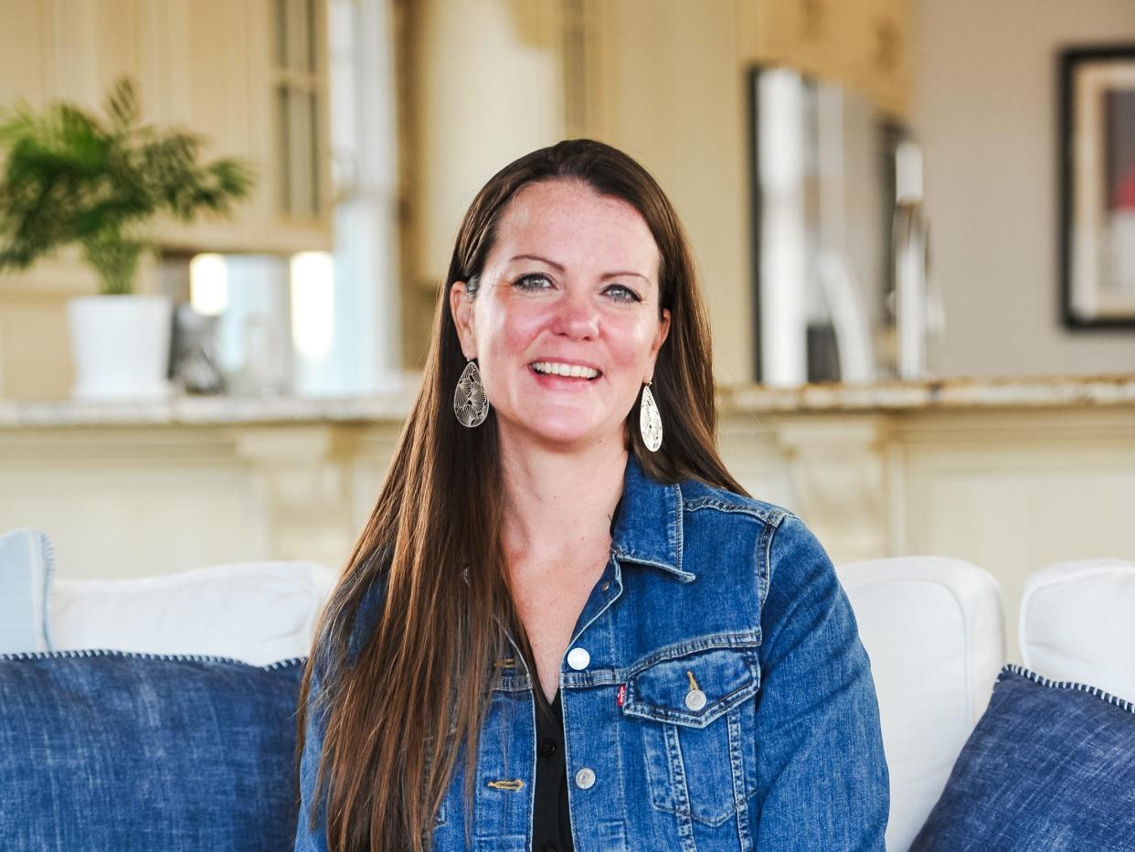 Melanie Obitz-Bukartek wearing a denim jacket and sitting on a couch.