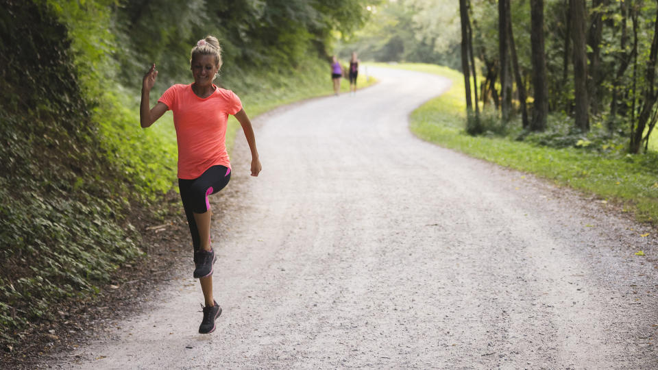 A woman skipping along a country road.