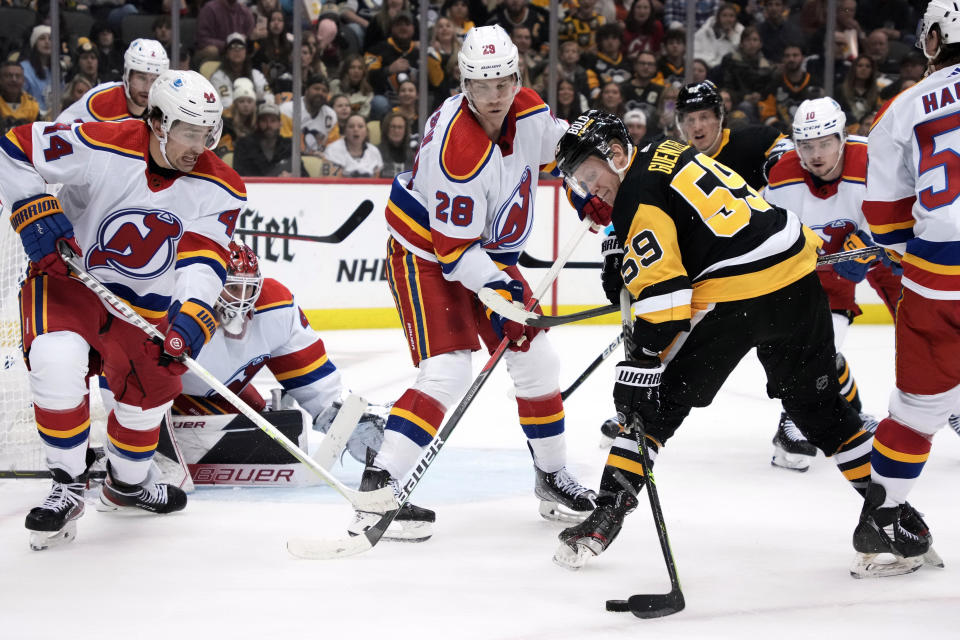 Pittsburgh Penguins' Jake Guentzel (59) can't get a shot off in front of New Jersey Devils goaltender Vitek Vanecek (41) with Nathan Bastian (14) and Damon Severson (28) defending during the second period of an NHL hockey game in Pittsburgh, Friday, Dec. 30, 2022. (AP Photo/Gene J. Puskar)