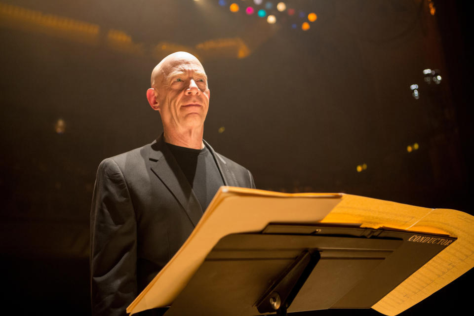 A man stands over a conductor's podium