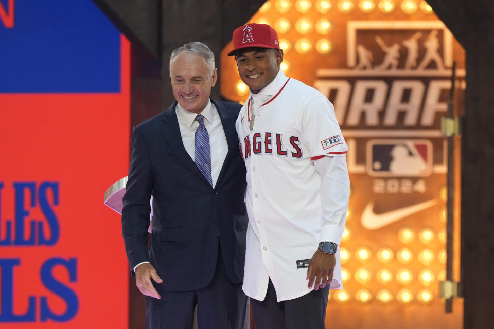 Major League Baseball Commissioner Rob Manfred, left, poses for a photo with Christian Moore, right, who was selected eighth overall by the Los Angeles Angels in the first round of the MLB baseball draft in Fort Worth, Texas, Sunday, July 14, 2024. (AP Photo/LM Otero)