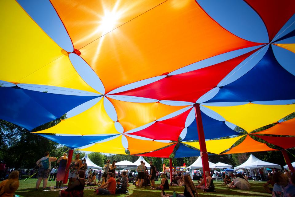 People rest under a shade structure as speakers take the stage at Eugene’s Pride in the Park Saturday, Aug. 13, 2022, at Alton Baker Park. 