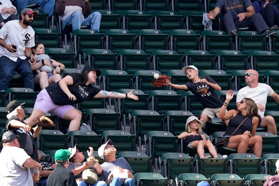 Baseball fans reach for a foul ball by Los Angeles Dodgers' Max Muncy in the upper deck of U.S. Cellular Field during the sixth inning of a baseball game between the Chicago White Sox and the Dodgers Thursday, June 9, 2022, in Chicago. (AP Photo/Charles Rex Arbogast)