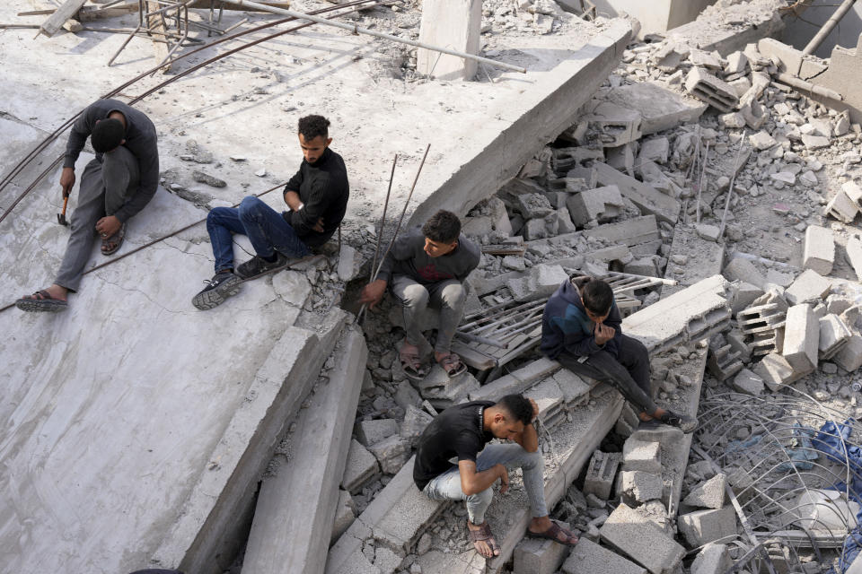 Palestinos sentados en los restos del edificio de la familia Al-Nadi que fue impactado por un bombardeo israelí, en el campo de refugiados de Nusseirat, en la Franja de Gaza, el viernes 8 de diciembre de 2023. (AP Foto/Adel Hana)