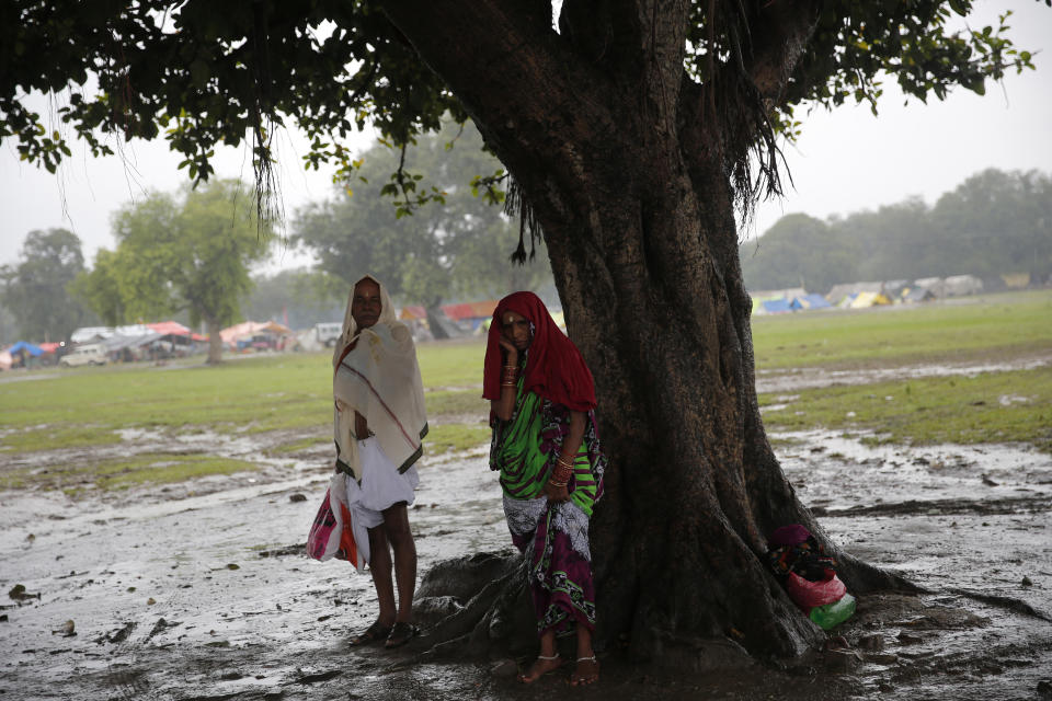 Hindu devotees take shelter from the rain under a tree in Prayagraj, in the northern Indian state of Uttar Pradesh, Saturday, Sept. 28, 2019. A heavy spell of retreating monsoon rains has flooded wide areas in northern India, killing dozens of people this week, an official said Saturday. Sandhaya Kureel, a spokeswoman of the Disaster Management and Relief Department, said most of the 59 fatalities were caused by house collapses, lightning and drowning in Uttar Pradesh state. (AP Photo/Rajesh Kumar Singh)