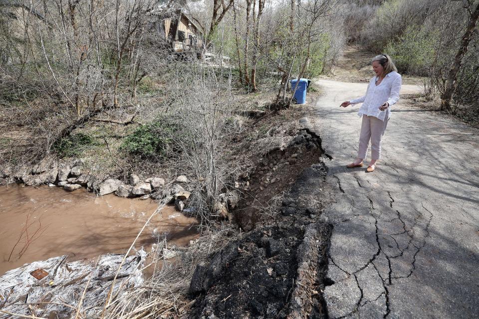 A neighbor looks at where water from Emigration Creek is going around the culvert under Cedarlof Lane, causing the road to erode, in Emigration Creek in Emigration Canyon on Tuesday, May 2, 2023.