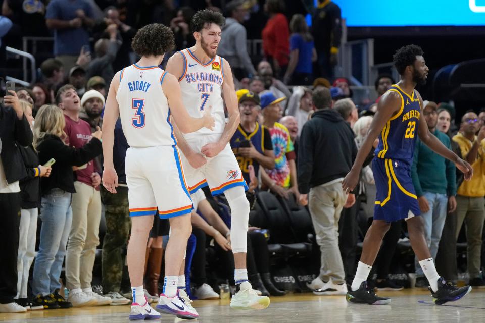Oklahoma City forward Chet Holmgren (7) celebrates with guard Josh Giddey (3) after making a 3-point basket at the second half buzzer to tie Saturday's game at the end of regulation as Golden State forward Andrew Wiggins (22) walks toward the bench in San Francisco.