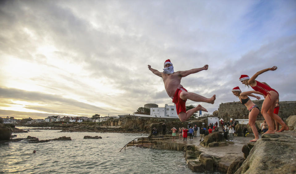 People take part in the annual Christmas Day swim at the Forty Foot bathing spot in Sandycove Dublin, Ireland, Friday Dec. 25, 2020. (Damien Storan/PA via AP)