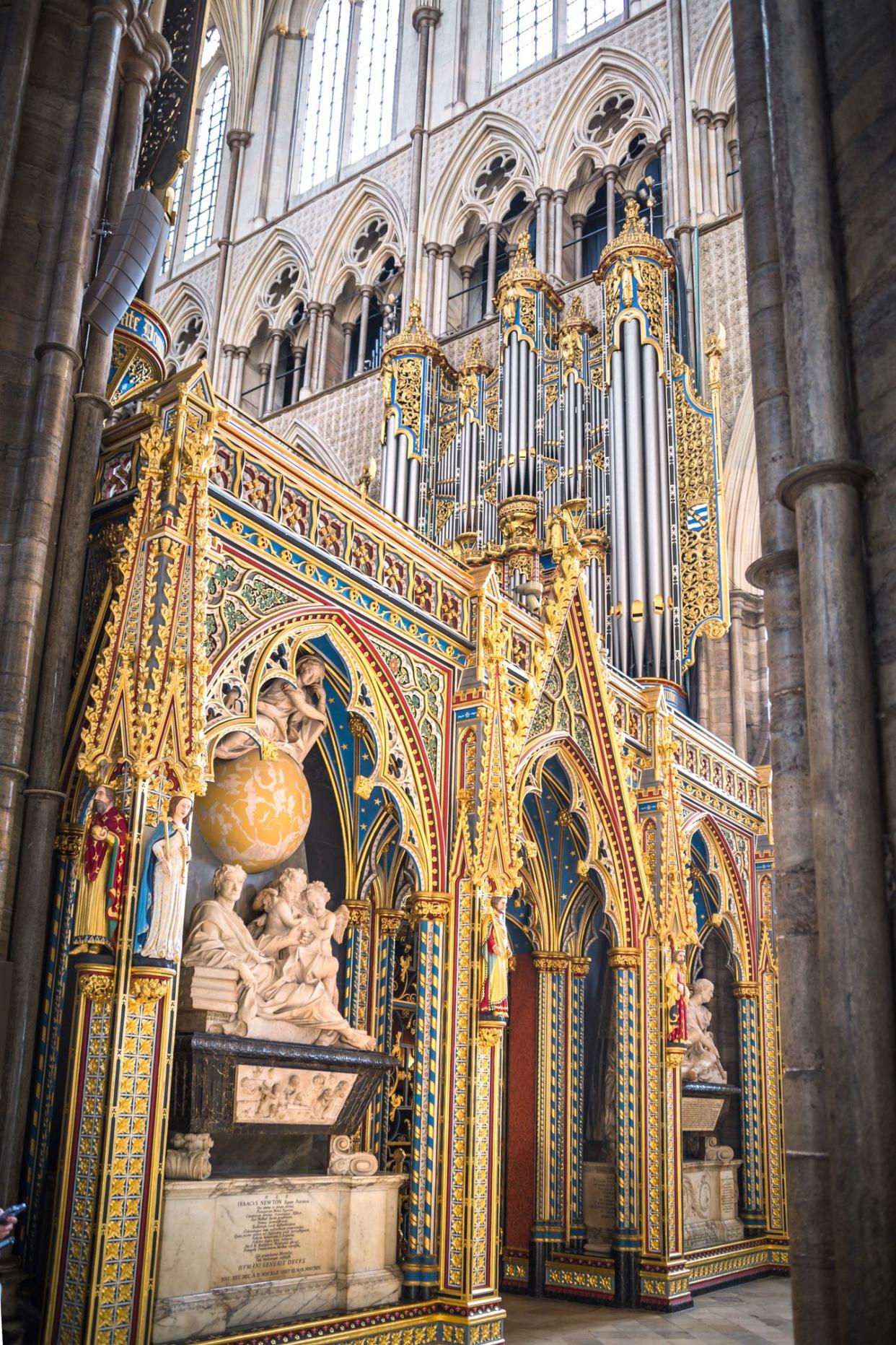 Sir Isaac Newton's tomb in the Altar of Westminster Abbey, London, ornate memorial sculpture dominate with golds and blue, with high church windows in the background