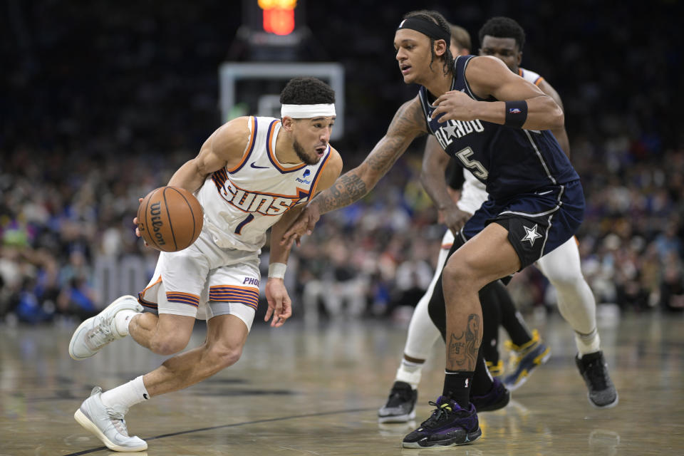 Phoenix Suns guard Devin Booker (1) drives to the basket while defended by Orlando Magic forward Paolo Banchero (5) during the second half of an NBA basketball game, Sunday, Jan. 28, 2024, in Orlando, Fla. (AP Photo/Phelan M. Ebenhack)