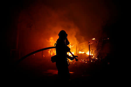 FILE PHOTO: A firefighter battles the Woolsey Fire in Malibu, California, U.S. November 9, 2018. The fire destroyed dozens of structures, forced thousands of evacuations and closed a major freeway. REUTERS/Eric Thayer/File Photo