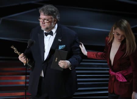 90th Academy Awards - Oscars Show - Hollywood, California, U.S., 04/03/2018 - Guillermo del Toro accepts the Oscar for Best Director for "The Shape of Water" from presenter Emma Stone (R). REUTERS/Lucas Jackson