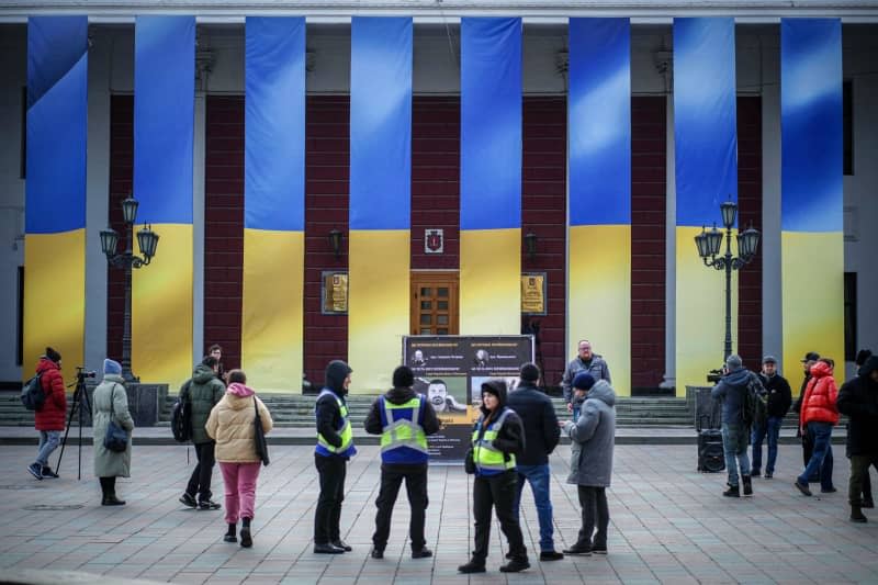 Journalists and police officers stand in front of the port city's town hall, which is decorated with Ukrainian flags. February 24, 2024 marks the second anniversary of the start of the Russian war of aggression against Ukraine. Kay Nietfeld/dpa