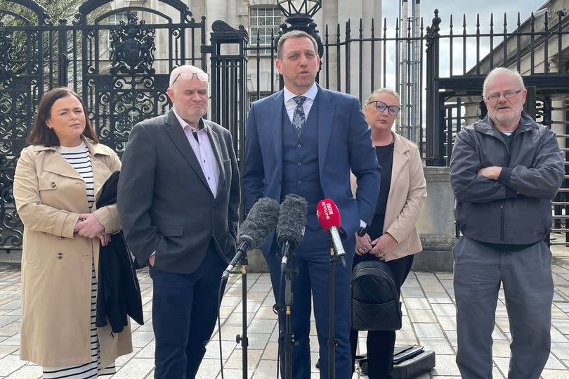 Solicitor Pádraig Ó Muirigh with members of the families of Peter Ryan (known as Michael) and Tony Doris outside court in front of mics