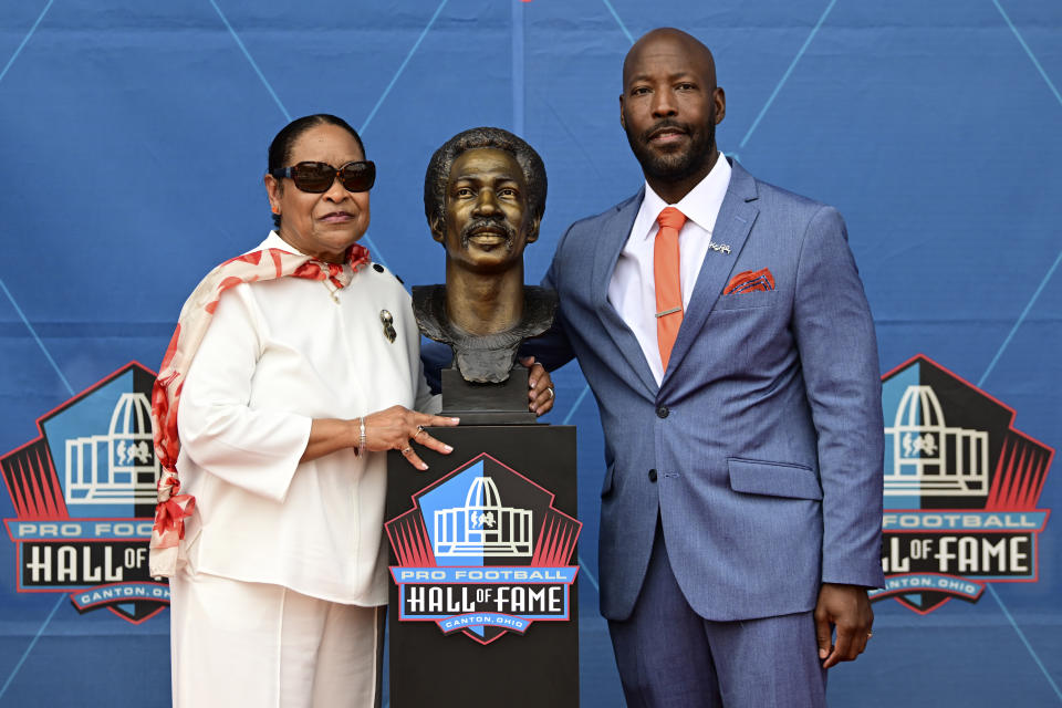 Barbara Riley, left, widow of Ken Riley, and his son Ken Riley II, pose with Ken Riley's bust during his induction into the Pro Football Hall of Fame in Canton, Ohio, Saturday, Aug. 5, 2023. (AP Photo/David Dermer)