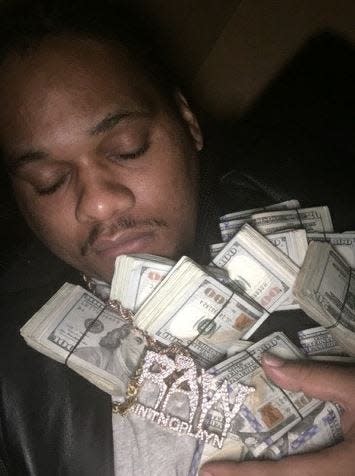 Rolando Antuain Williamson, one of Birmingham, Alabama's most notorious drug traffickers, posed with stacks of $100s and custom-made diamond jewelry displaying his initials (Photo: Federal court evidence)