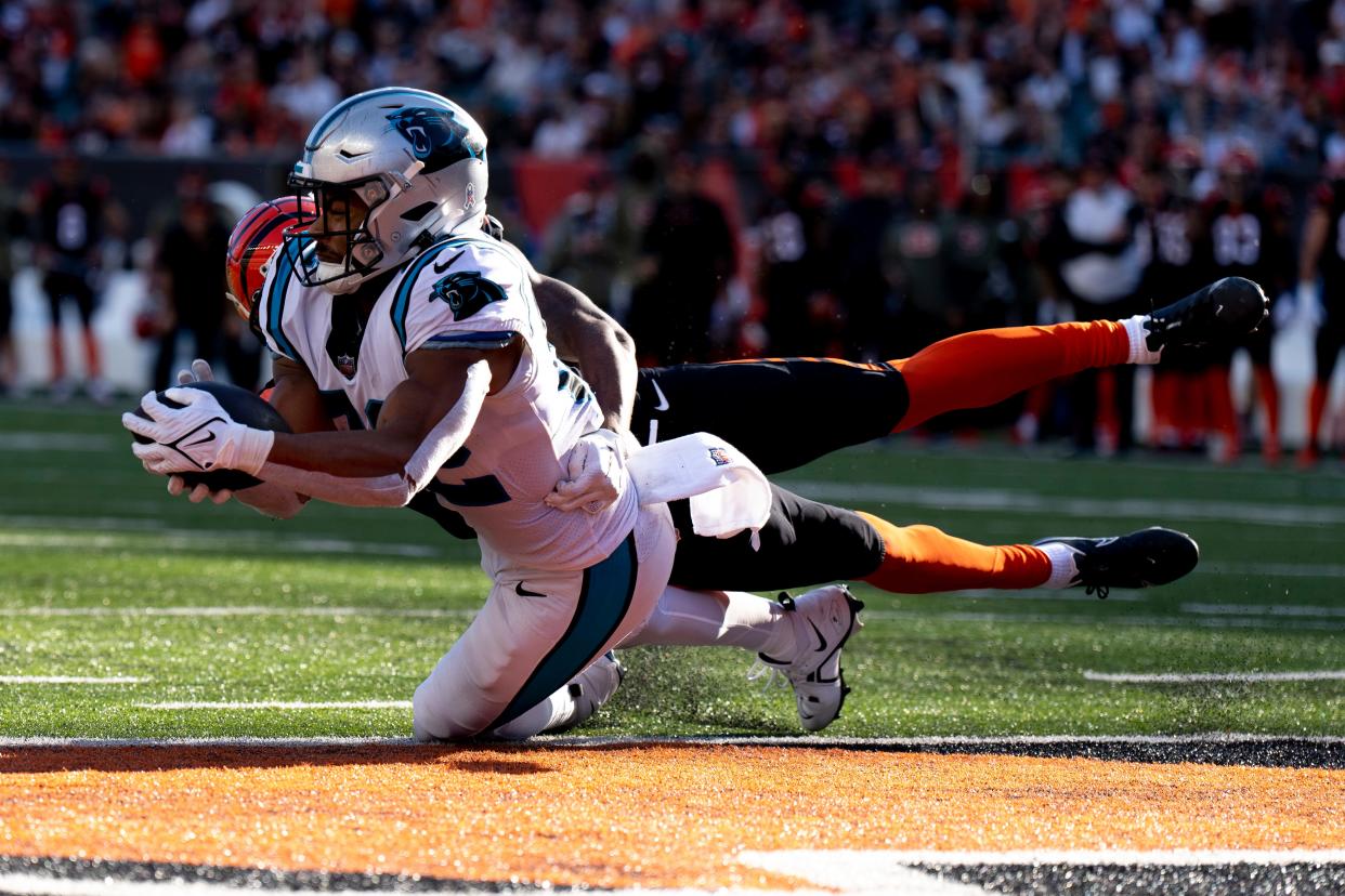 Carolina Panthers tight end Tommy Tremble caches a touchdown pass as Cincinnati Bengals safety Dax Hill attempts to stop him.