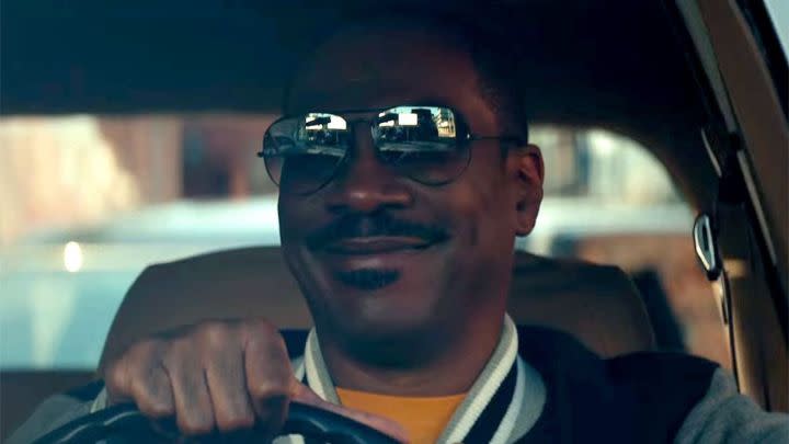 Eddie Murphy as Axel Foley smiling while driving a car in Netflix's Beverly Hills Cop: Axel F.