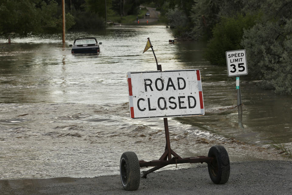 A road is closed from floodwaters along the Clarks Fork Yellowstone River near Bridger, Mont., on Monday, June 13, 2022. The flooding across parts of southern Montana and northern Wyoming forced the indefinite closure of Yellowstone National Park just as a summer tourist season that draws millions of visitors annually was ramping up. (AP Photo/Emma H. Tobin)