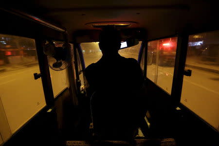 A man who takes commuters from their homes to a bus station in Yanjiao, Hebei province, China drives his electric tricycle November 13, 2015.