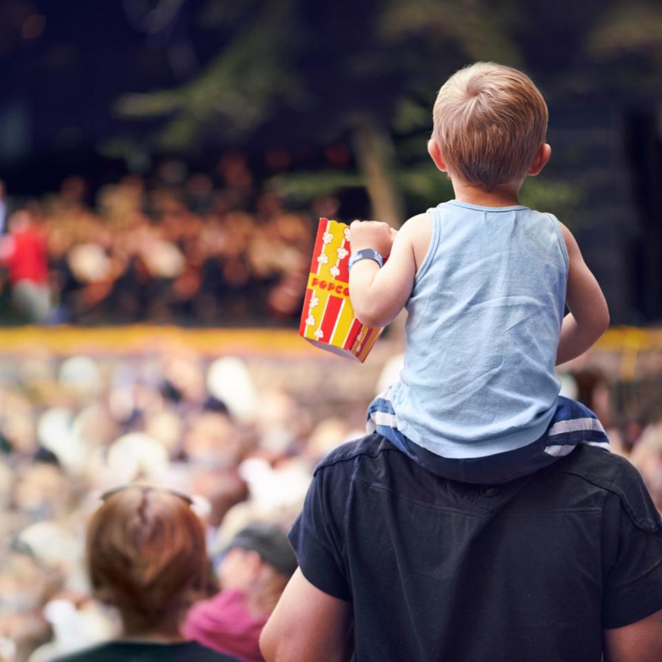 young boy sitting on his fathers shoulders at an outdoor festival