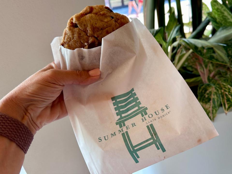 hand holding up a bag with a cookie from the cookie bar at summer house in disney springs