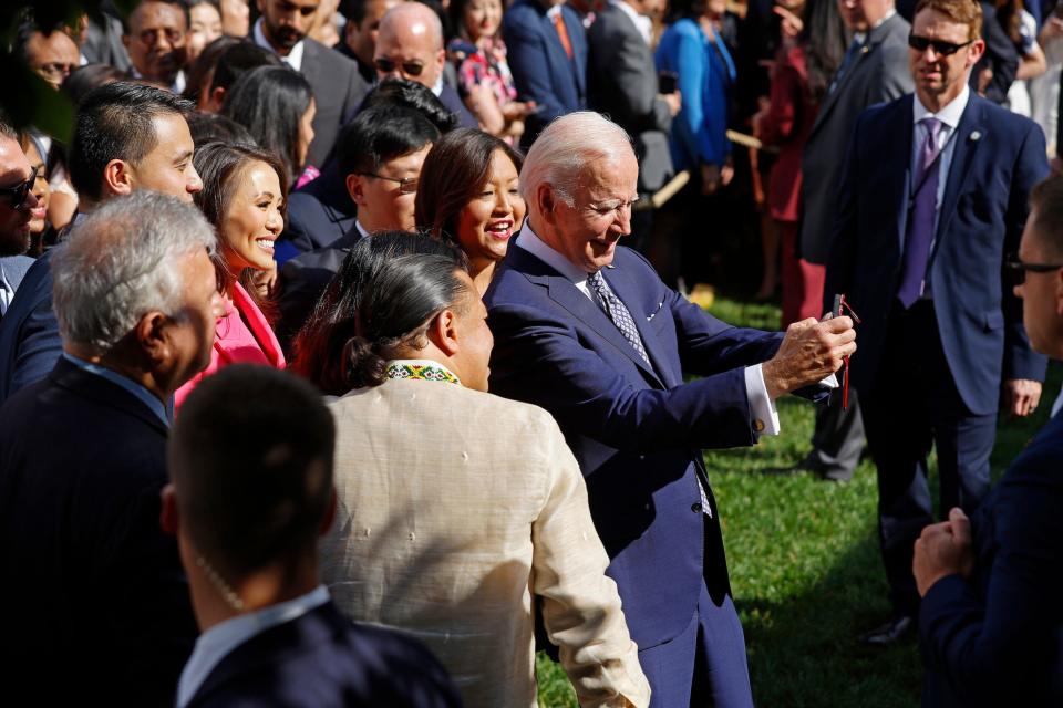President Joe Biden uses a guest's phone to take a selfie