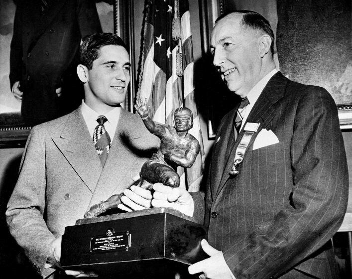 FILE - Notre Dame quarterback Johnny Lujack, left, recceives the Heisman Memorial Trophy from Wilbur Jurden, president of the Downtown Athletic Club in New York, Dec. 10, 1947. Lujack, the Heisman Trophy winner who led Notre Dame to three national championships in the 1940s, died in Florida on Tuesday, July 25, 2023, following a brief illness. He was 98. (AP Photo/Jacob Harris, File)