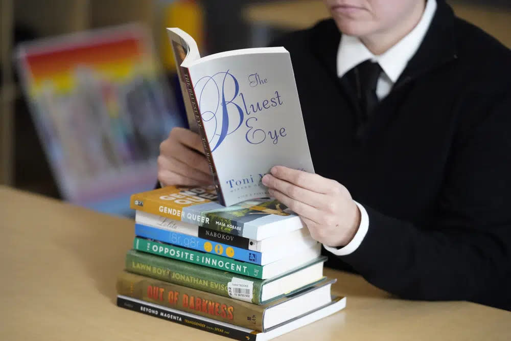 Amanda Darrow, director of youth, family and education programs at the Utah Pride Center, poses with books, including “The Bluest Eye,” by Toni Morrison, that have been the subject of complaints from parents, on Dec. 16, 2021, in Salt Lake City. (AP Photo/Rick Bowmer, File)