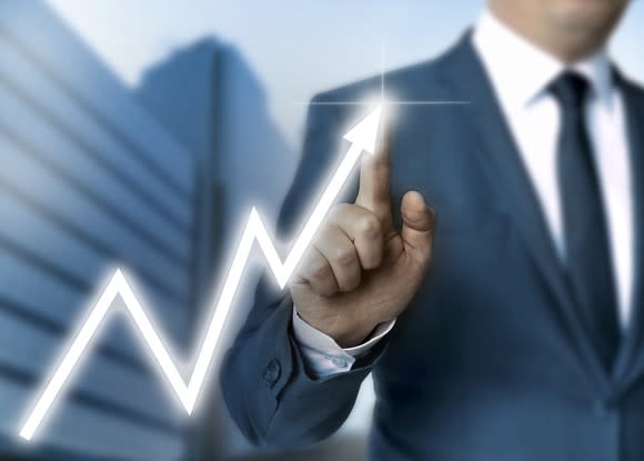 Man in suit drawing a line chart indicating sharp gains