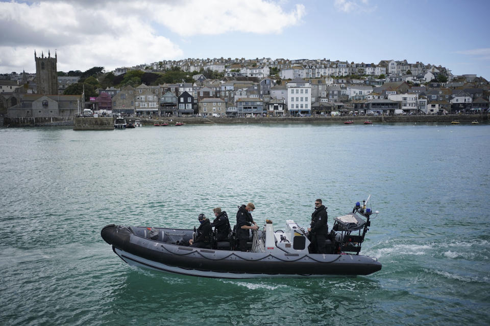 FILE - In this Monday, June 7, 2021 file photo, police officers patrol the harbour in St. Ives, Cornwall, England ahead of the G7 summit that takes place in nearby Carbis Bay. Towering steel fences and masses of police have transformed the Cornish seaside as leaders of the Group of Seven wealthy democracies descent for a summit near St. Ives in Cornwall, a popular holiday destination. A huge frigate dominates the coastline, armed soldiers guard the main sites and some 5,000 extra police officers have been deployed to the area. (Aaron Chown/PA via AP, File)