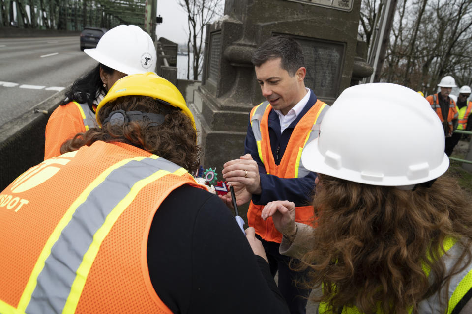 U.S. Transportation Secretary Pete Buttigieg tries to light candles on a cupcake commemorating the Interstate 5 bridge's 107th birthday near the Washington state entrance to the bridge, Tuesday, Feb. 13, 2024, in Vancouver, Wash. Buttigieg toured the century-old Interstate 5 bridge that connects Portland, Ore., with southwest Washington state, a vital but earthquake-vulnerable structure that's set to be replaced as part of a multibillion-dollar project supported by federal funding. (AP Photo/Jenny Kane)